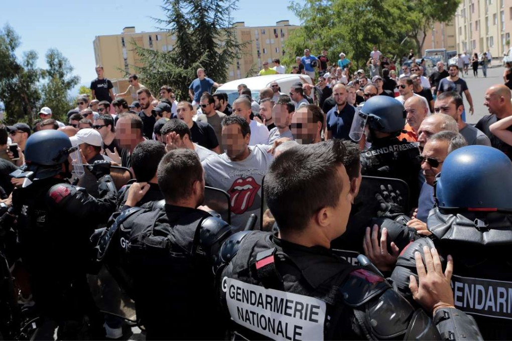 Protesters are surrounded by policemen in Lupino, Corsica, Sunday, a day after a violent fight at the seaside involving North African families and local youths. Photo: AFP