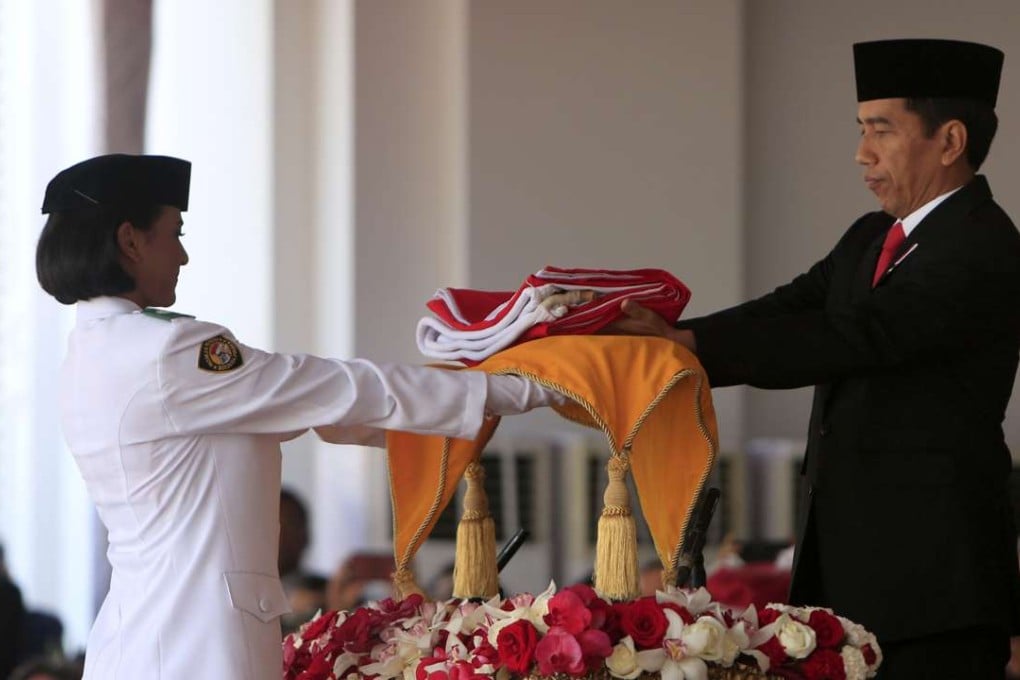 Indonesian President Joko Widodo (R) hands a folded national flag to a flag raiser during celebrations marking the 71th anniversary of Indonesia's independence day at the Presidential Palace in Jakarta. Photo: EPA