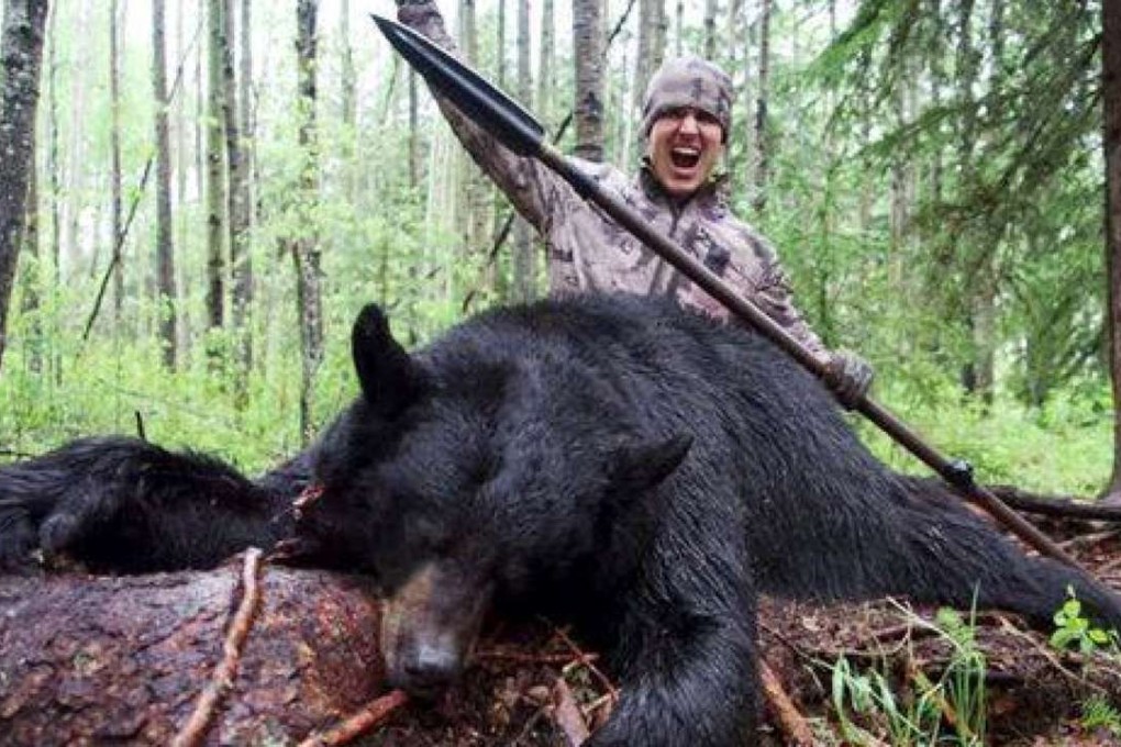 Joh Bowmar celebrates his killing of a black bear, which he speared to death. Photo: YouTube