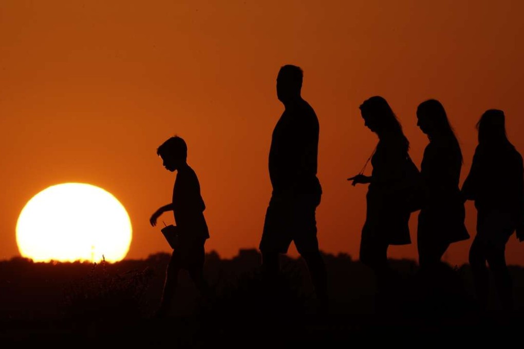 The sun sets beyond visitors to Liberty Memorial in Kansas City on Thursday, July 21. Photo: AP