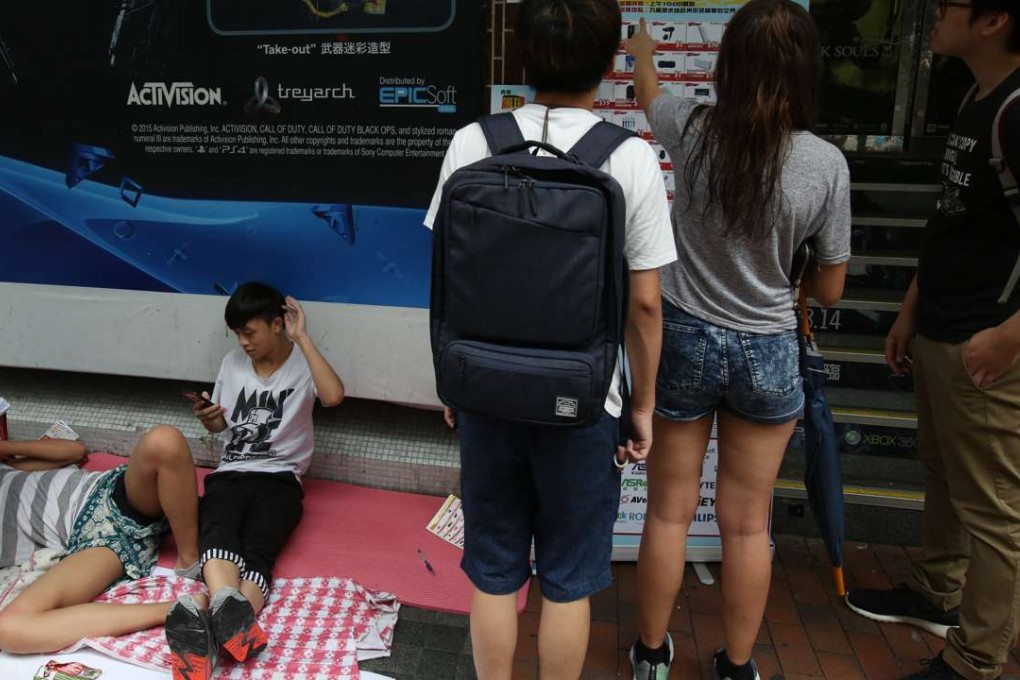 15-year-old Lee Ming (sitting) and his schoolmate have been queuing outside Golden Computer Arcade in Sham Shui Po since Sunday. Photo: Nora Tam