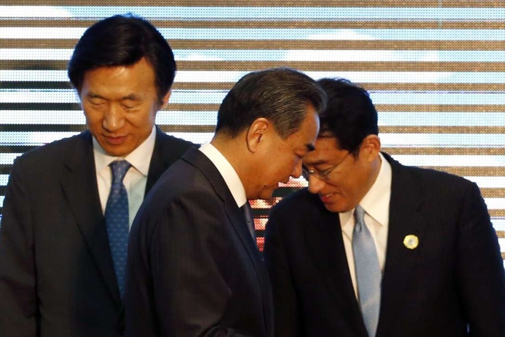 China's Foreign Minister Wang Yi (centre) walks past his South Korean counterpart Yun Byung-se (left) to address Japan's Fumio Kishida (right) during an Asean meeting in Laos last month. Photo: EPA