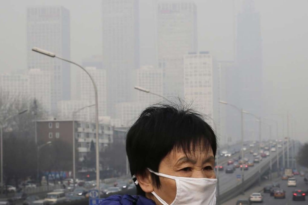 A woman wearing a mask for protection against pollution walks on a pedestrian overhead bridge as office buildings in Central Business District of Beijing are shrouded with smog. Photo: AP