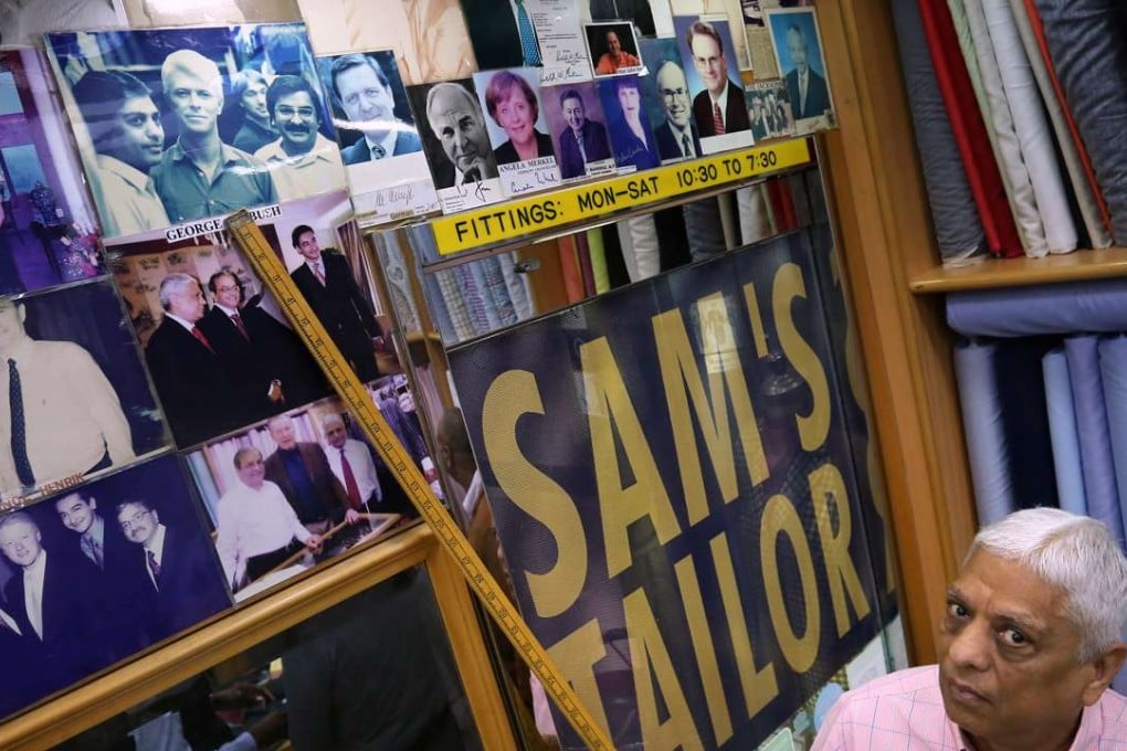 Sam's Tailor boss Manu Melwani points to a photo he has of the late David Bowie visiting the shop. Picture: Jonathan Wong