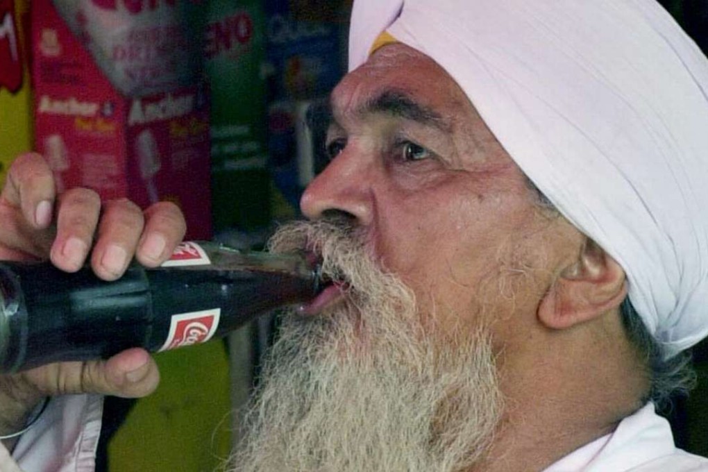 File photo of an Indian man drinking Coca-Cola. Photo: AFP