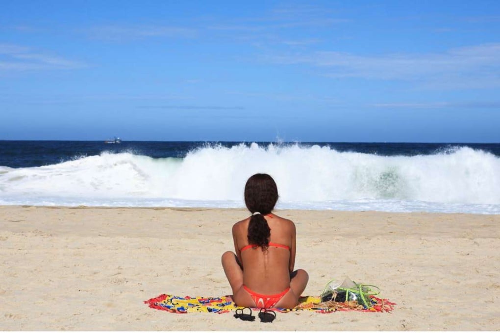 A Rio resident looks out at the waves on Copacabana Beach. Several Brazilian women complain of a ‘meat market’ atmosphere, saying that tourists seem to think all locals are single and willing. Photo: Alamy.