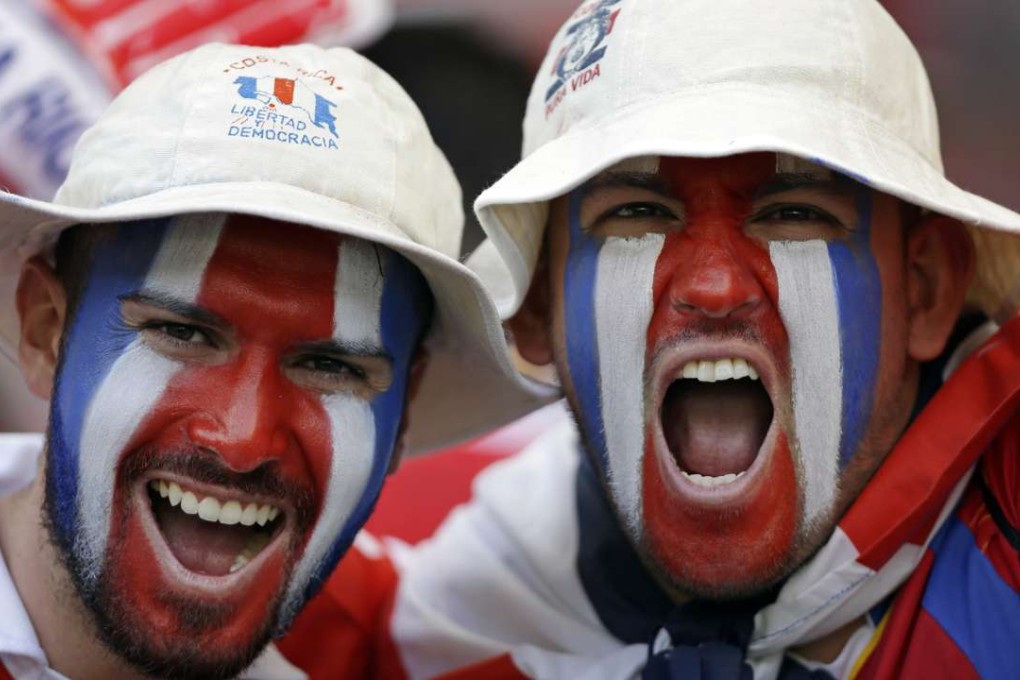 Costa Rica fans with the national colours painted on their faces celebrate at a soccer match. Photo: AP