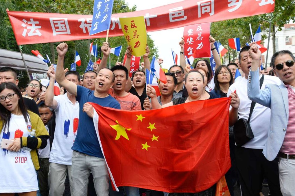 People hold a Chinese national flag as they march during a demonstration in Paris on Sunday in response to the killingof tailor Zhang Chaolin. Photo: Agence France-Presse