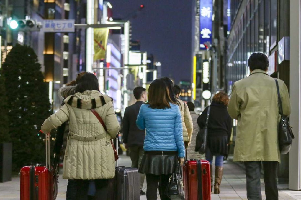 Chinese tourists carry suitcases packed with purchases during their bulk buying, also called as 'Bakugai' in central Tokyo, Japan. Photo: EPA