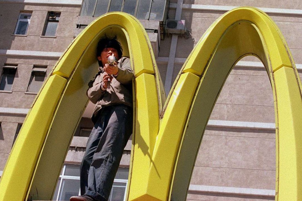 A worker repairs a McDonald's sign on the streets of Beijing. The fast food chain is looking to sell its mainland Chinese franchise operations. Photo: Mark Ralston