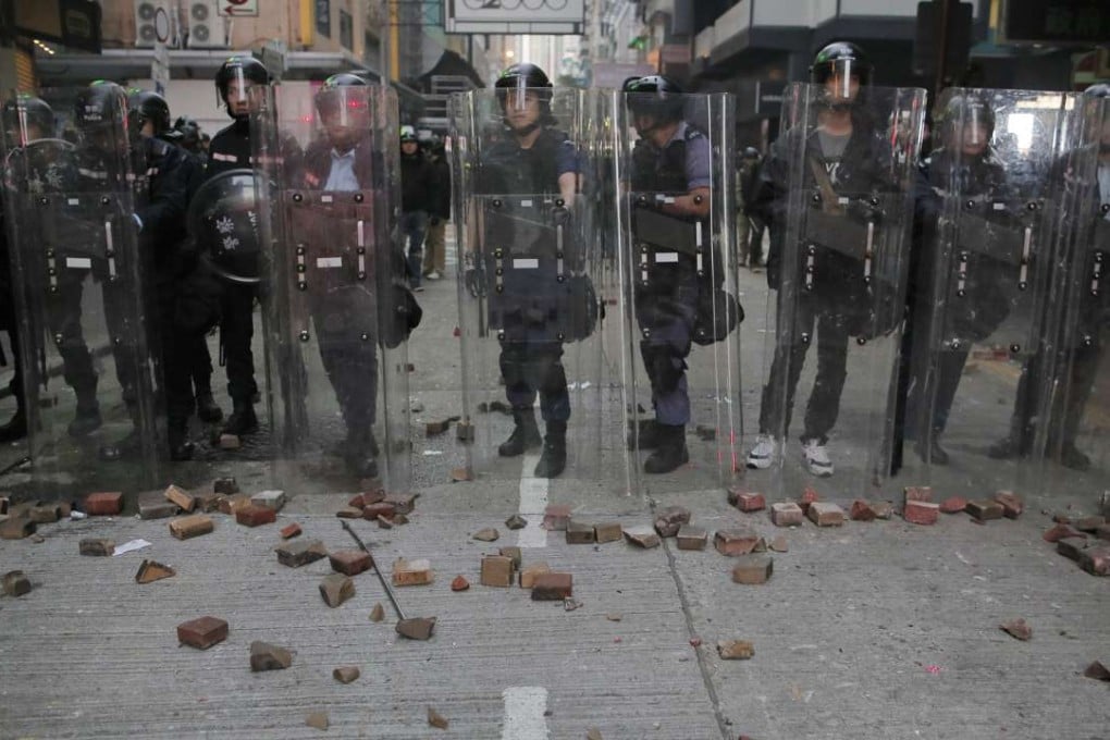 Police stand guard as protesters throw bricks during the Mong Kok riot in February. Photo: AP