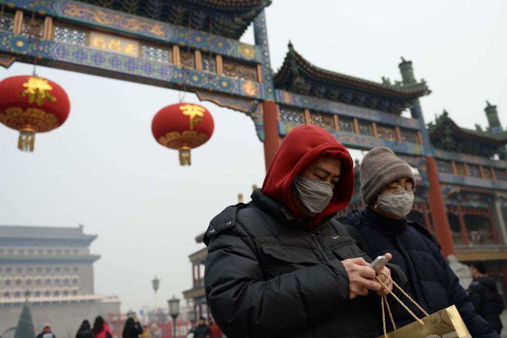 Visitors protect themselves from the polluted air as they make their way along Qianmen in Beijing. China and the US account for about 38 per cent of global greenhouse gas emissions. Photo: AFP