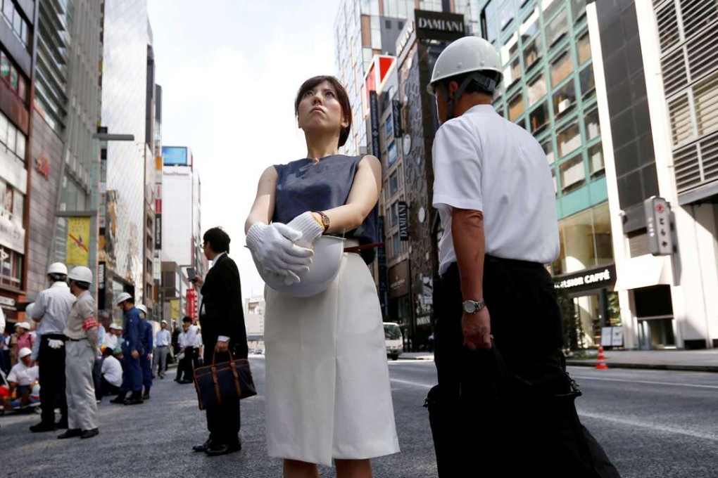 People wearing and holding helmets take part in a drill simulating a 7.2 magnitude earthquake in Tokyo, Japan on August 26. Photo: Reuters