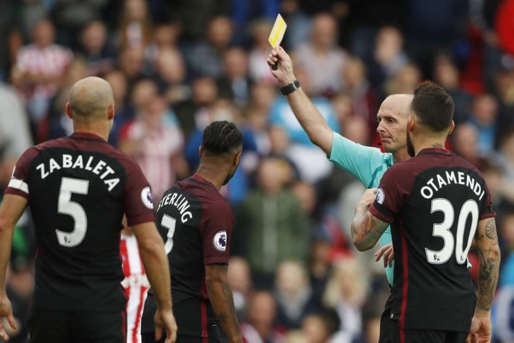 Referee Mike Dean shows a yellow card to Manchester City's Raheem Sterling. Photo: Reuters