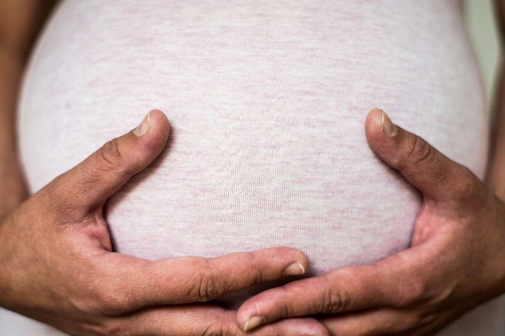 A heavily pregnant woman holds her belly. Photo: EPA