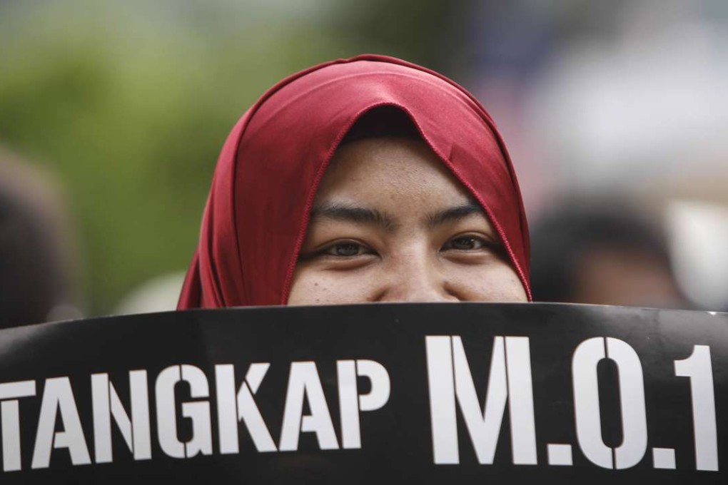 A Malaysian Muslim woman holds up a placard translating "arrest M.O.1" during a rally. Photo: AP