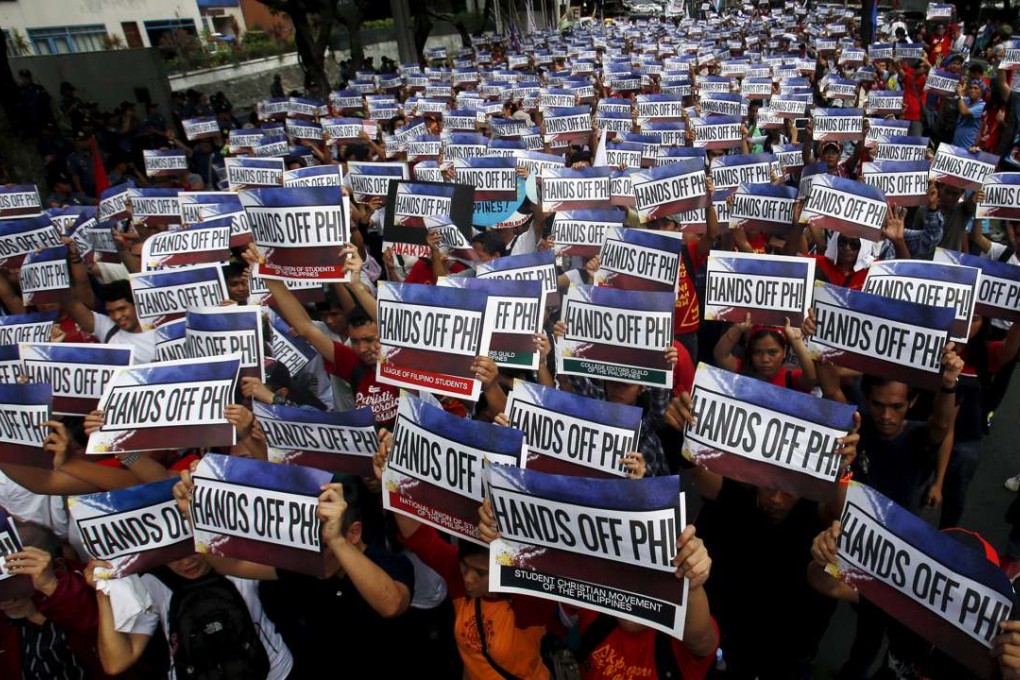 Activists hold up signs that read, "Hands Off PH!" during a protest over the South China Sea disputes outside the Chinese consulate in Makati City, Manila. Photo: Reuters