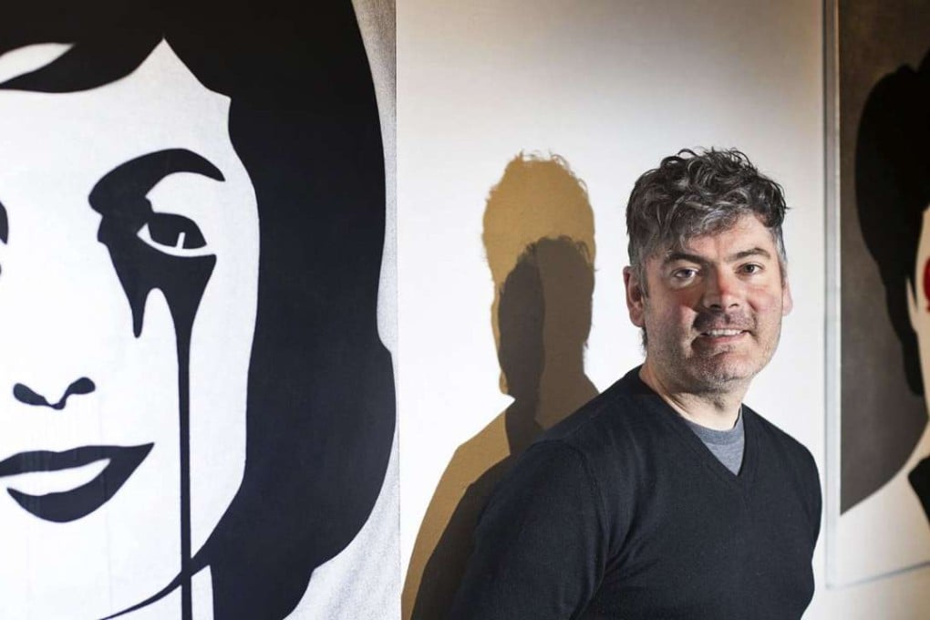 Artist Pure Evil (real name Charles Uzzell Edwards) poses next to some of his works at Above Second Gallery in Hong Kong.