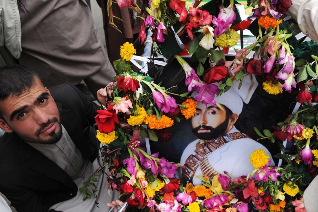 A supporter of former Afghan King Habibullah Kalakani carries a wreath bearing Kalakani’s likeness during an attempted re-burial ceremony in Kabul on Thursday. Photo: EPA