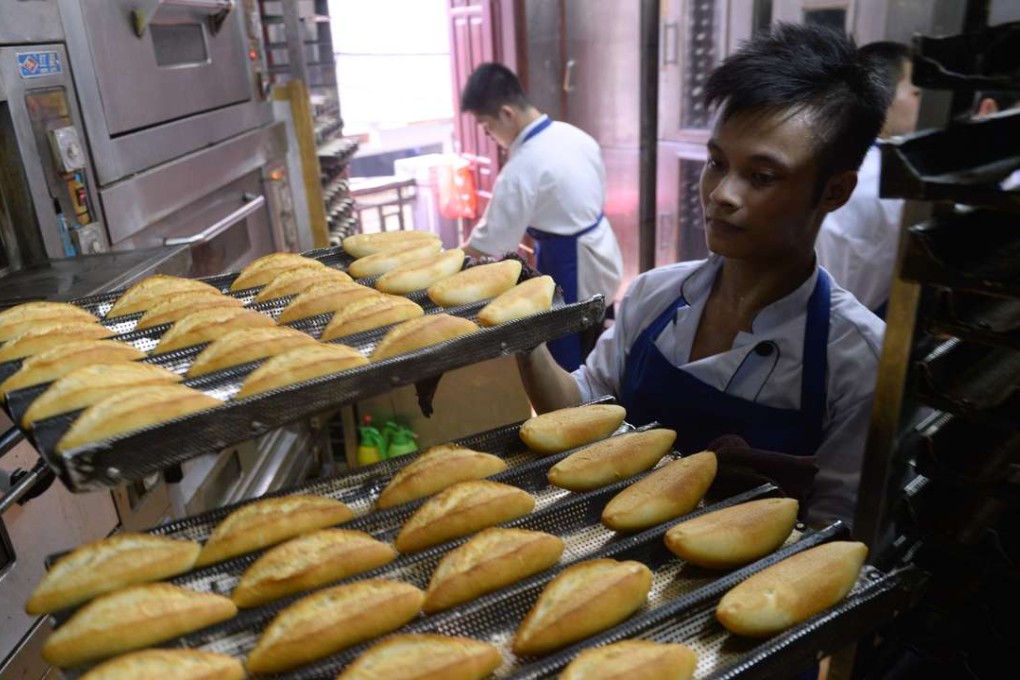 An employee carries plates with baked bread at Hoan Boulangerie in Hanoi. Photo: AFP