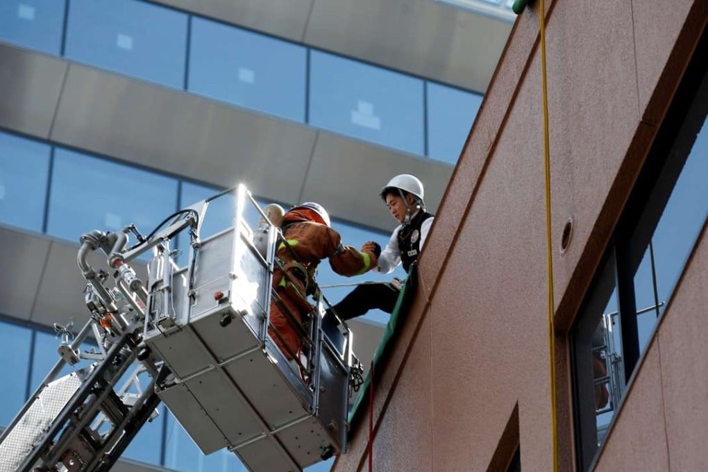 A fire worker in a crane rescues a man role-playing as a person who is isolated atop of a building in an earlier drill simulating a 7.2 magnitude earthquake in Tokyo, on August 26. Photo: Reuters