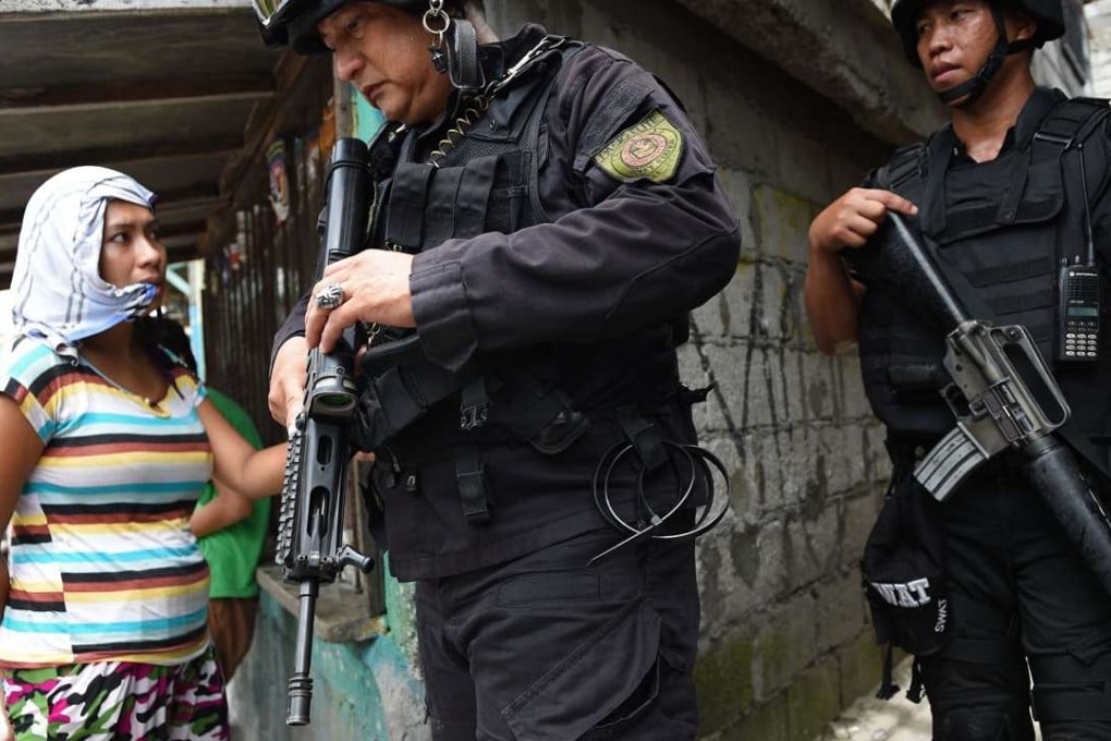 Police Special Weapons And Tactics (SWAT) personnel walk past a resident after an operation against illegal drugs in Pasig City, Manila. Photo: AFP