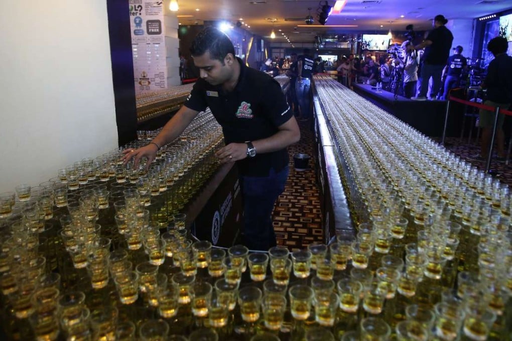 A crew memberssets up the glasses before an attempt to make the world's longest domino drop shot on Monday in Dubai’s Huddle Sports Bar & Grille. Photo: AP