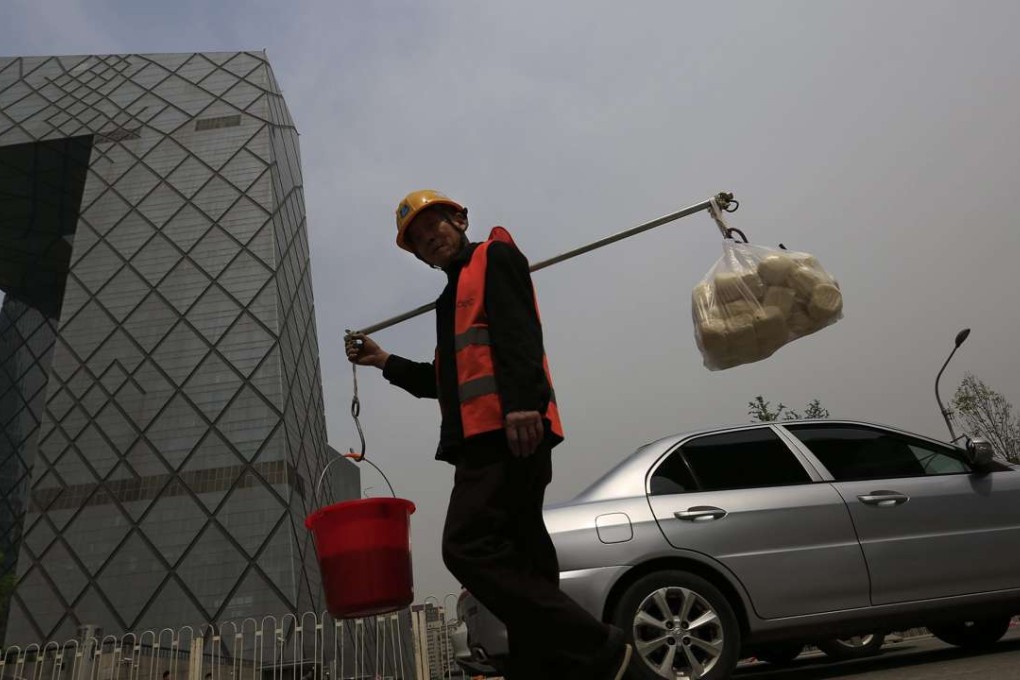 A construction worker carries supplies past Beijing’s iconic CCTV Tower. The Chinese economy advanced an annual 6.7 per cent in the second quarter, slightly above market expectations. Photo: EPA