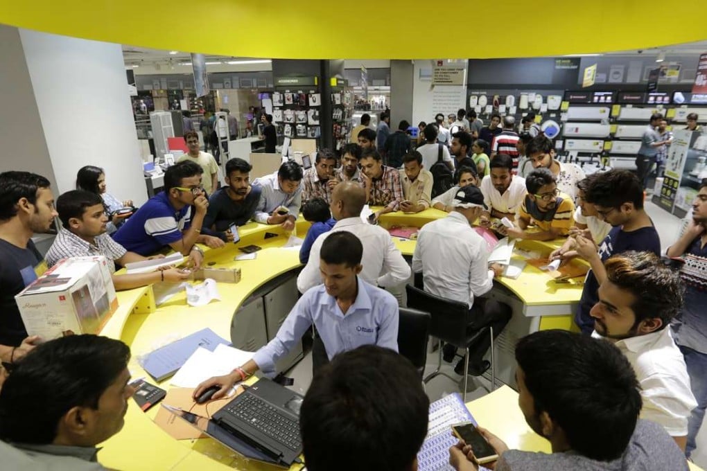 Employees serve customers at a service counter at a Reliance Digital store in New Delhi. Photo: Bloomberg