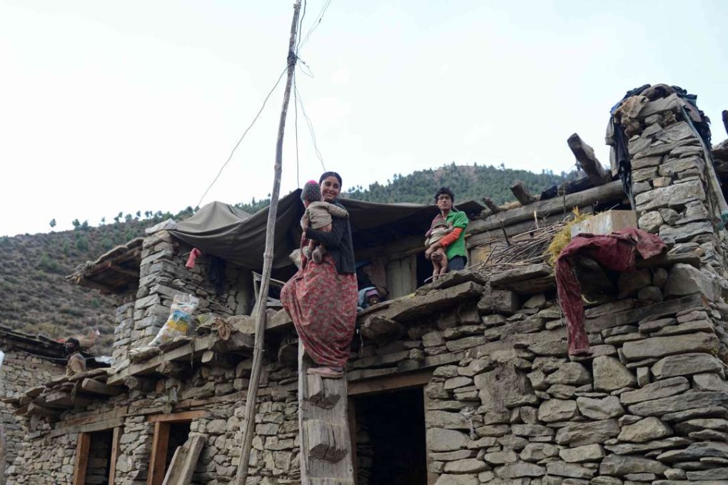 A Nepalese resident holds one of her children on the roof of a home in Simikot. Photo: AFP
