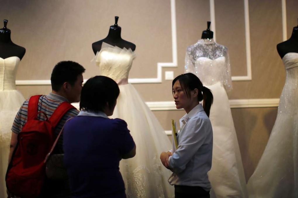 A couple talk to a vendor at a wedding dress stand during a wedding exhibition in downtown Shanghai. Photo: Reuters