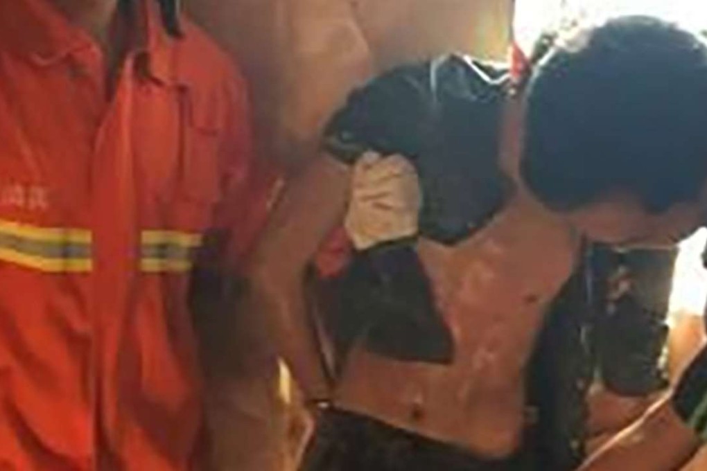 Firemen rescue a man who became trapped in a toilet vent. Photo: SCMP Pictures