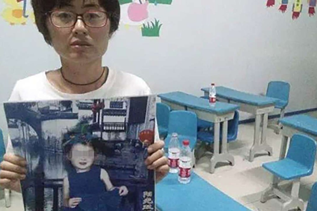 The unnamed Chinese mother of the dead four year-old girl, Ting Ting, holds up a photograph of her daughter. Photo: SCMP Pictures