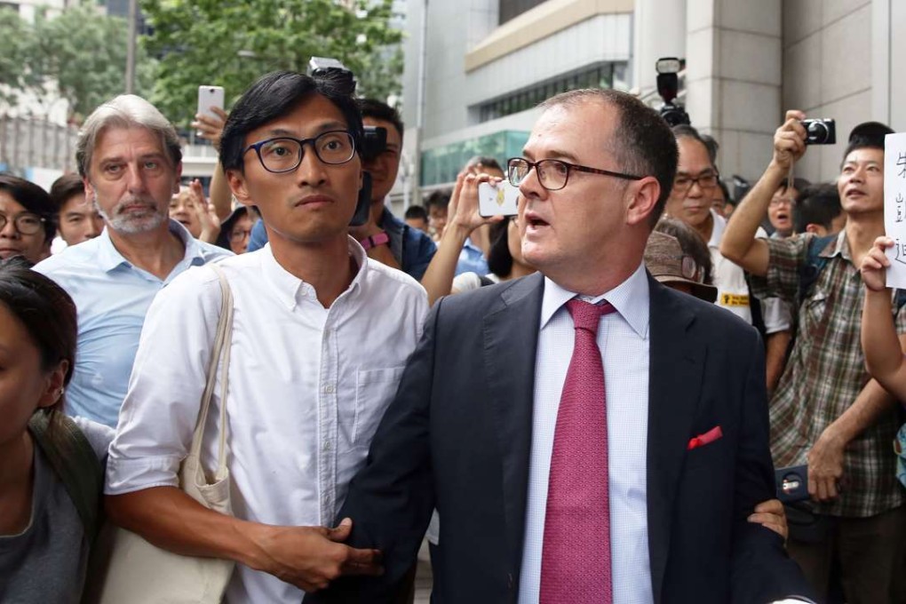 Eddie Chu Hoi-dick (centre, in white shirt) accompanied by his legal adviser, appears at police headquarters in Wan Chai. Photo: Sam Tsang