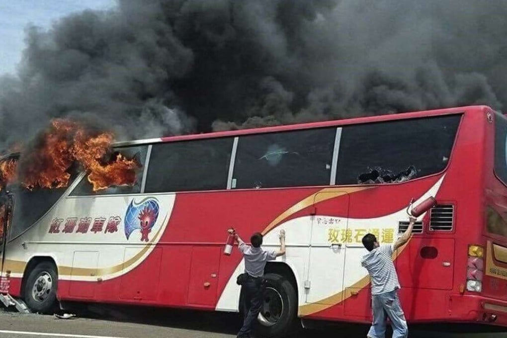 A policeman and another man try to break the windows of a burning tour bus on the side of a highway in Taoyuan, Taiwan, on July 19. Photo: AP
