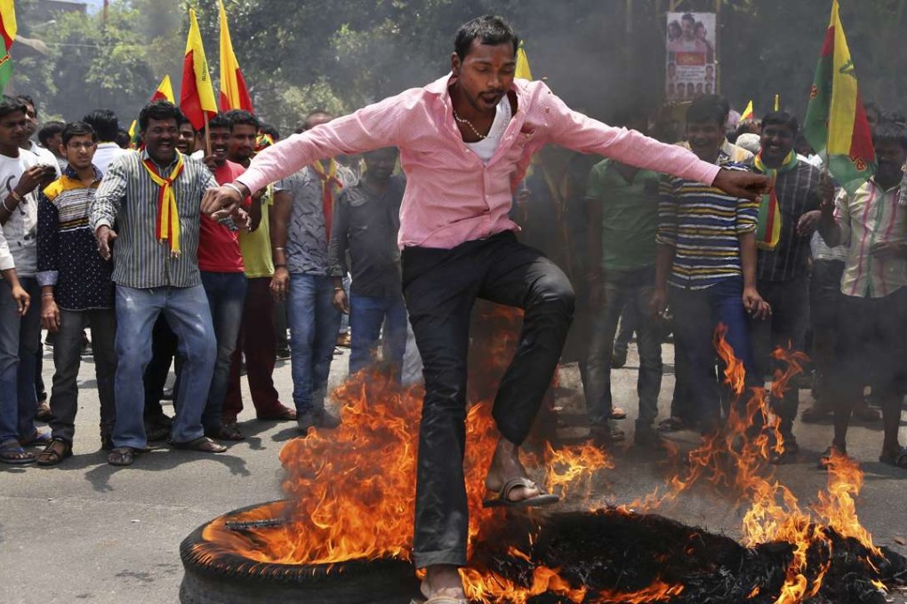An activist jumps over a burning tire and an effigy of Chief Minister of Tamil Nadu state Jayaram Jayalalitha during a protest against a recent Supreme Court order on a river water sharing dispute, in Bangalore. Photo: Ap