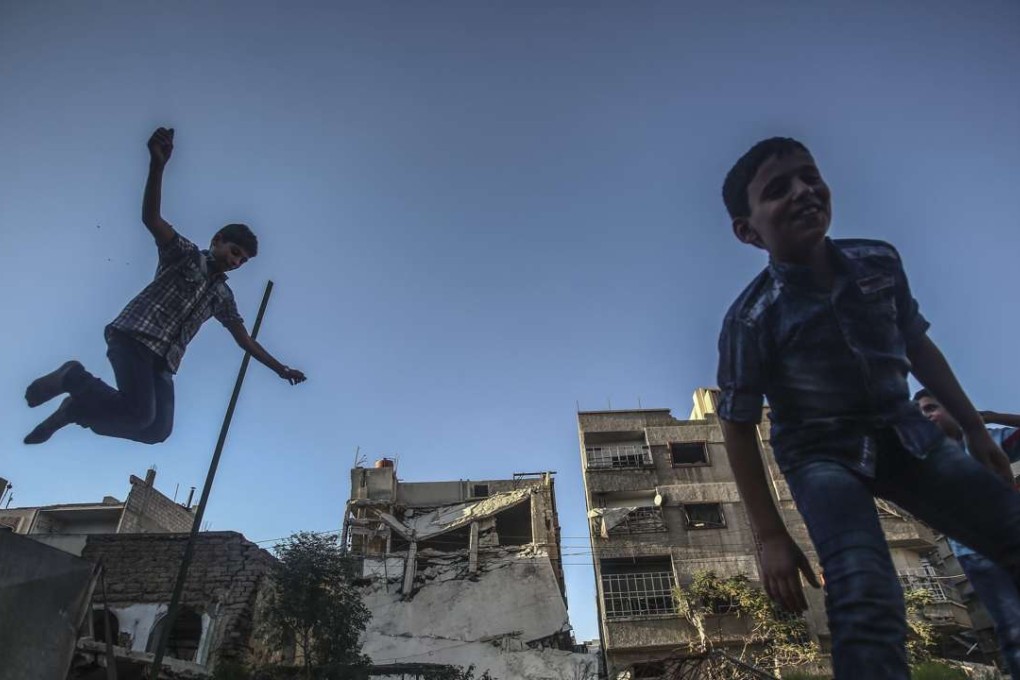 Syrian children playing on a trampoline during the second day of Eid Al Adha in Douma, outside Damascus, on Tuesday, amid a ceasefire brokered by the US and Russia. Photo: EPA