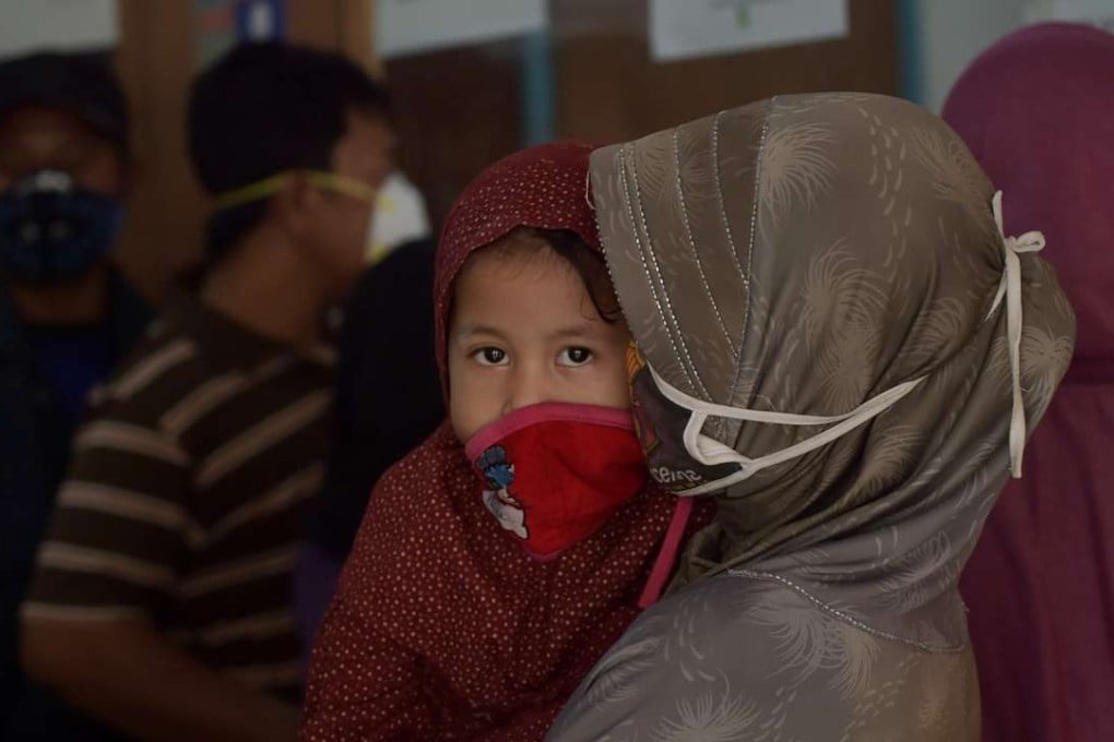 An Indonesian mother holding her daughter as they wait at a health centre following thick haze in Pekanbaru in Riau province. Photo: AFP
