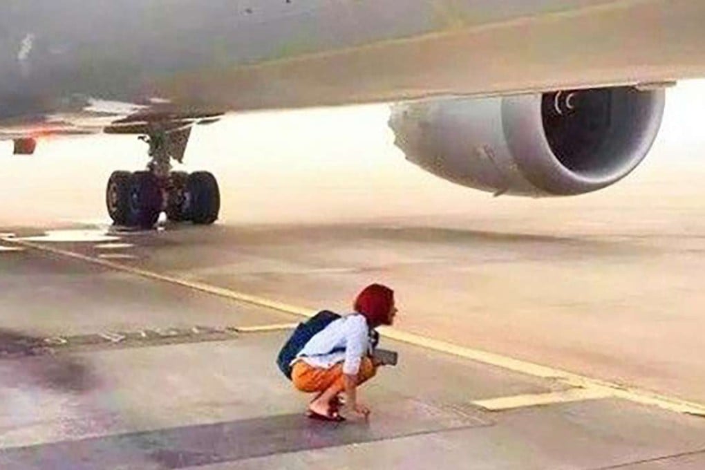 The Chinese woman stages a protest on the airport runway under the aircraft after arriving too late for boarding on Saturday. Photo: SCMP Pictures