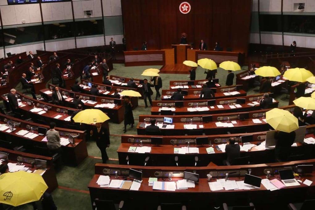 Pro-democracy lawmakers hold up symbolic yellow umbrellas as they leave the Legislative Council chamber in protest against the second round of consultation on the 2017 chief executive election on January 7 last year. Photo: David Wong