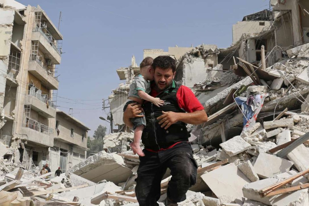 A Syrian man carries a toddler after rescuing him from the rubble of a destroyed building following a reported air strike in the Qatarji neighbourhood of Aleppo on Wednesday. Photo: AFP