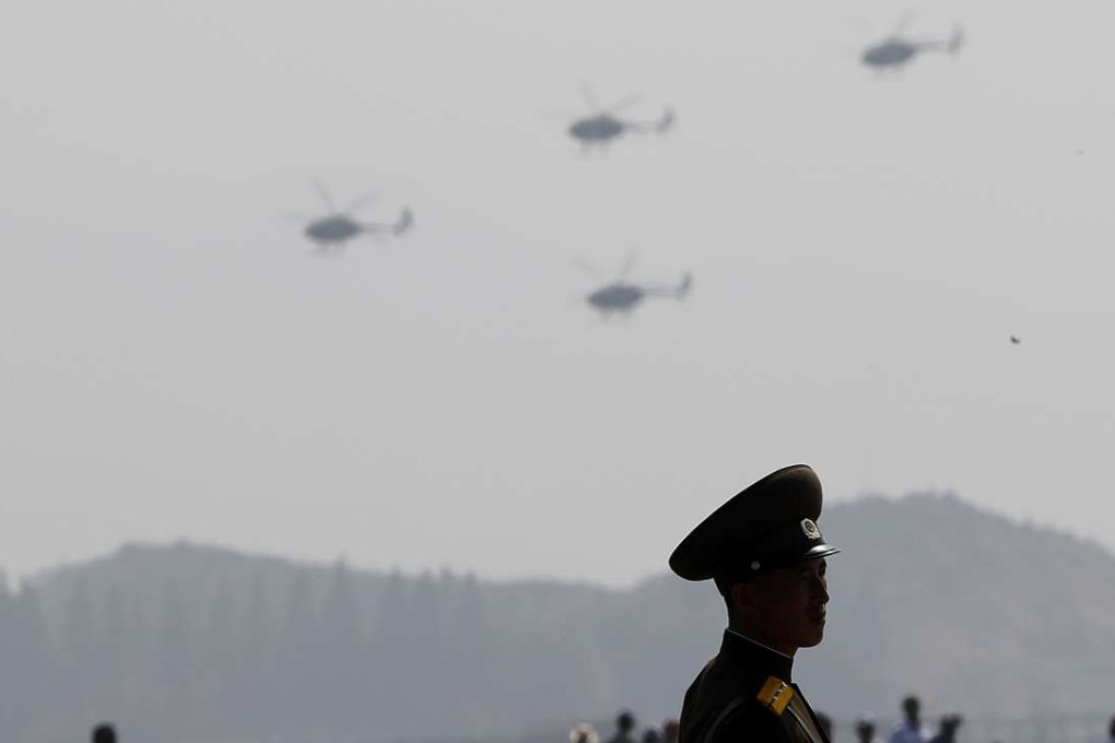 A North Korean military soldier stands guard as Hughes MD-500 helicopters fly past during an aerial display. Photo: AP