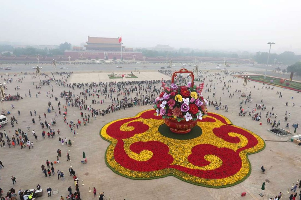 A pall of air pollution hangs over Tiananmen Square in the capital yesterday as visitors admire a huge flower display. Photo: Xinhua