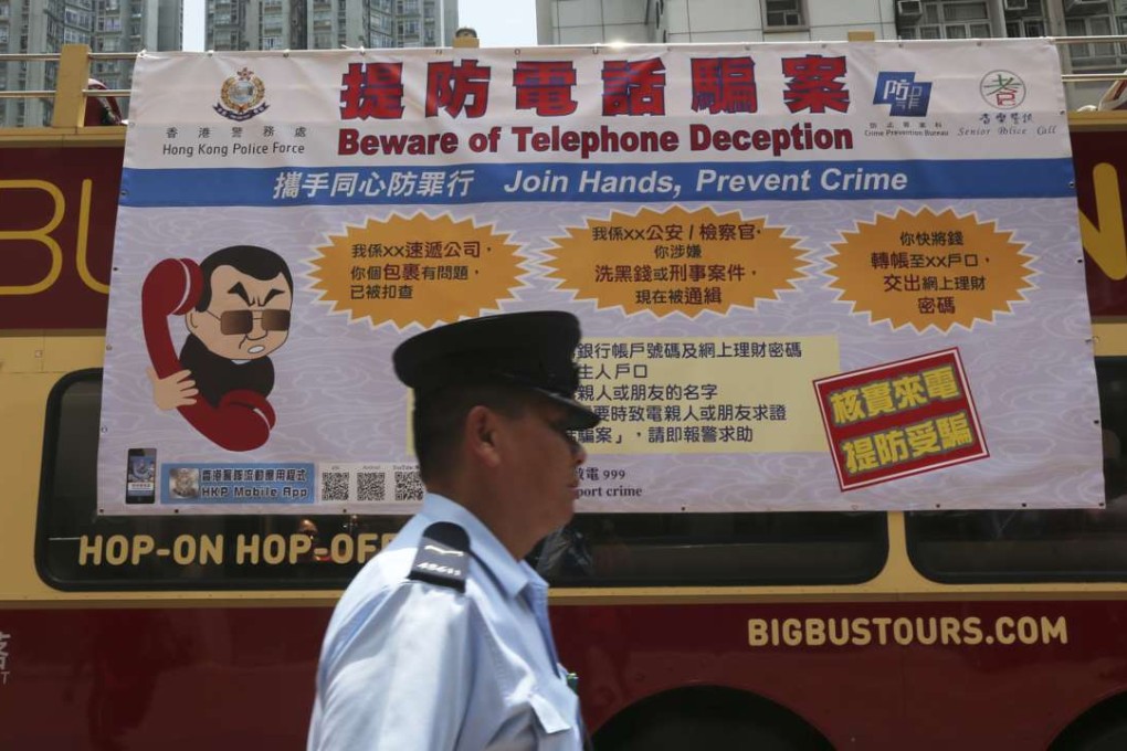 A policeman in Lam Tin in front of a government ad cautioning against falling prey to phone scams. Photo: David Wong