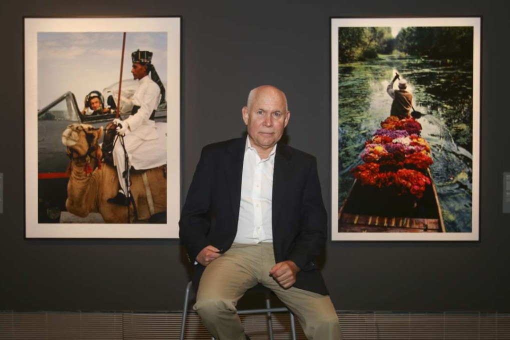 Photographer Steve McCurry poses in front of two of the shots featured in a Hong Kong exhibition of his work and that of his boyhood inspiration and fellow Magnum photographer Brian Brake. Photo: Chen Xiaomei