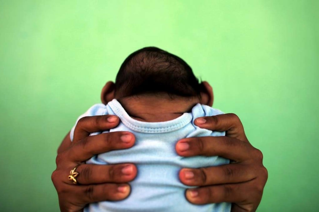A four-month-old baby born with microcephaly is held by his mother in front of their house in Olinda, near Recife, Brazil. Pregnant women infected by the mosquito-borne Zika virus run the risk of giving birth to babies with this defect. Photo: Reuters