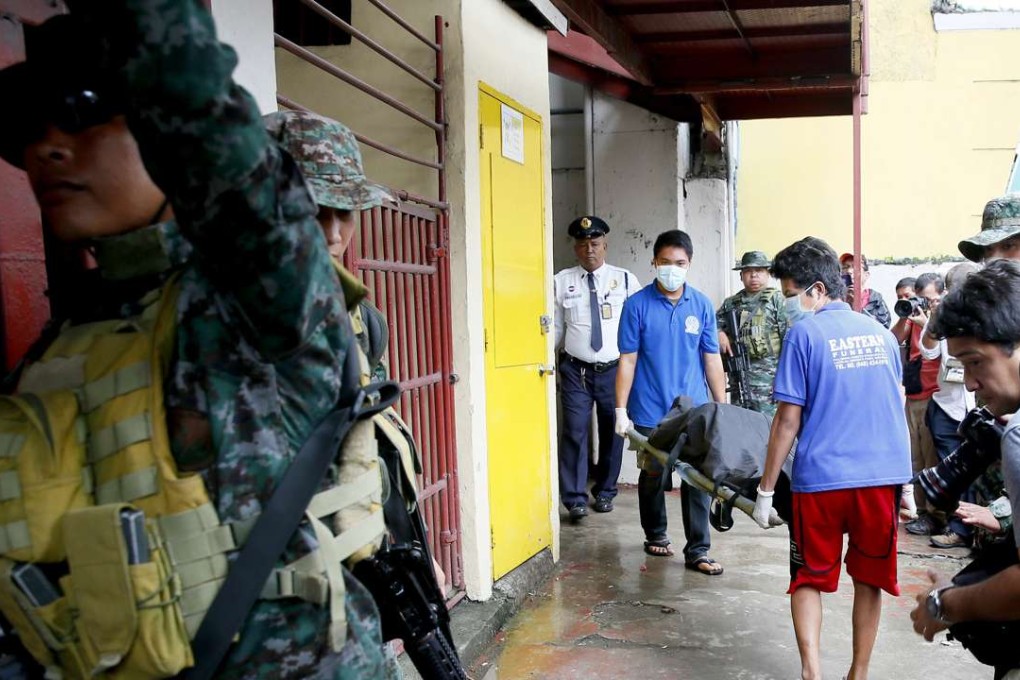 Workers carry the body of an inmate after he was killed in a prison riot inside the national penitentiary. Photo: AP
