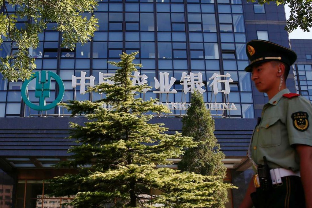 A paramilitary policeman walks past the Agricultural Bank of China building in Beijing. Photo: Reuters