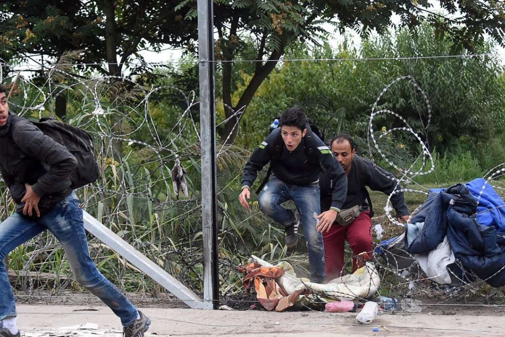Migrants cross through a hole in a barbed-wire fence an they run into the forest at the Hungarian-Serbian border near Roszke in September 2015. File photo: AFP