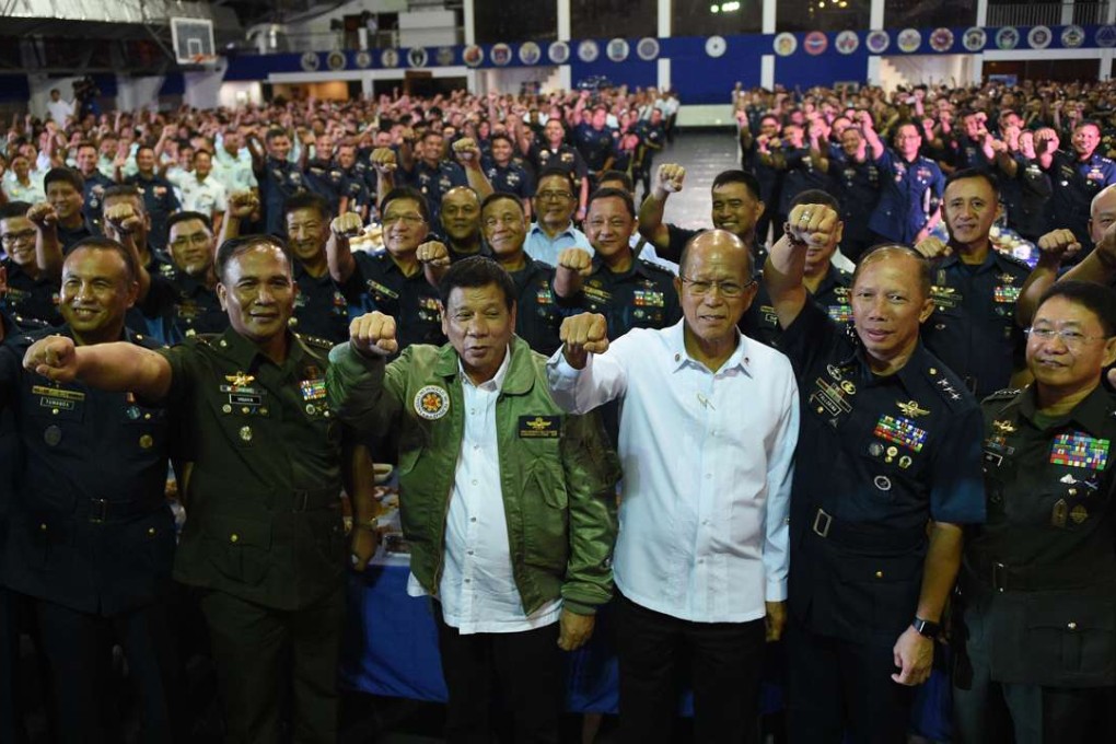 Philippine President Rodrigo Duterte, centre, wearing an air force jacket given to him as a gift, poses with defence secretary Delfin Lorenzana, fourth right, and military chief General Ricardo Visaya, third left. Photo: AFP